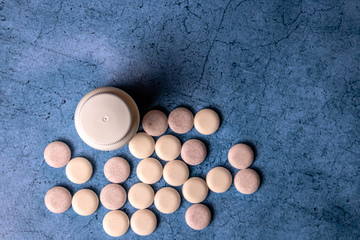 set of round vitamin next to a white bottle on a blue background