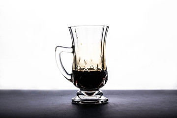 transparent crystal cup and dark liquid, on white background.