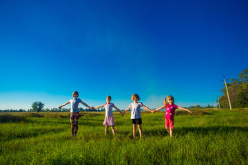 Fototapeta na wymiar Large group of kids running in summer field with blue sky background