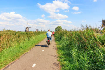 Obraz premium Kinderdijk, Netherlands - August 17, 2018: Tourists Cycling At Kinderdijk