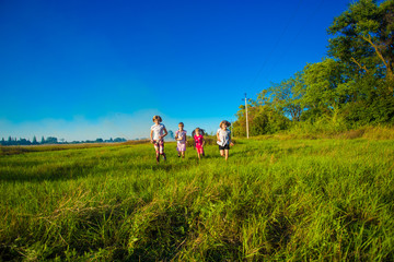 Large group of kids running in summer field with blue sky background