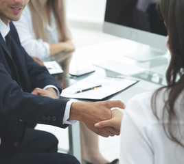 closeup.handshake trading partners,sitting behind a Desk