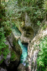 Deep cave with river trough it. In bohinj Slovenia. Trees and clear blue water