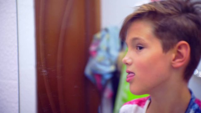 Little funny boy teenager who combs her hair in front of the bathroom mirror.close-up portrait.Small depth of field