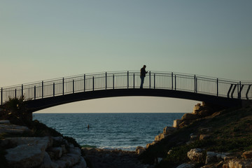 Fototapeta premium Silhouettes of people on a bridge, Tel Aviv, Israel