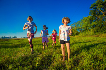 Fototapeta premium Large group of kids running in summer field with blue sky background