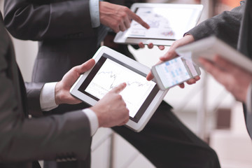 Businessmen at meeting presenting charts on smartphone, tablet