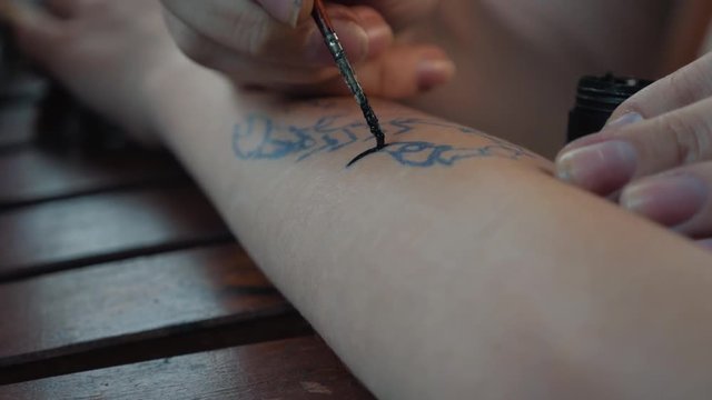 Drawing a child's tattoo on his hand with black paint. Beautiful drawing on a children's hand