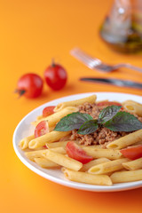 Pasta Fettuccine Bolognese with tomato sauce and basil in white dish on the orange background.
