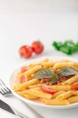 Pasta Fettuccine Bolognese with tomato sauce and basil in white dish on the white background.