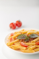 Pasta Fettuccine Bolognese with tomato sauce and basil in white dish on the white background.