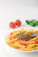 Pasta Fettuccine Bolognese with tomato sauce and basil in white dish on the white background.
