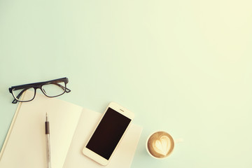 Minimalistic flat lay composition of black & white laptop computer keyboard, cell phone gadget, cup of coffee & folded glasses on textured wooden desk table background. Workspace top view, copy space