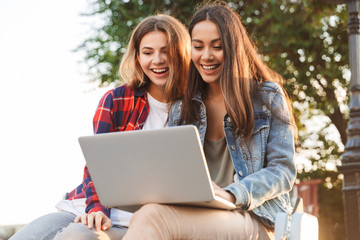 Two smiling young girls friends sitting together