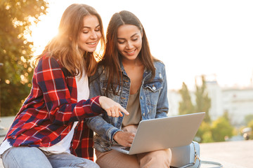 Two cheerful young girls friends sitting together