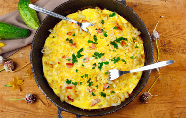 Traditional rustic omelette with bacon, pasta and greens .  Copy space