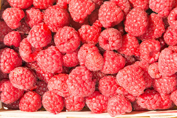 Heap of ripe juicy raspberries in wicker market box