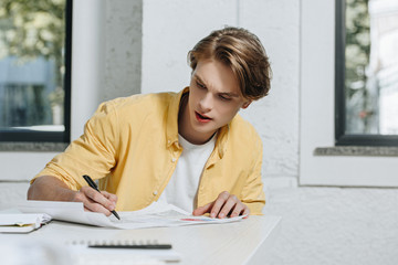 handsome businessman writing something to documents in office