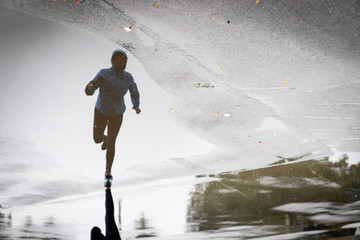 Fototapeta na wymiar Runner woman running in Park in the rain. Jogging training for marathon.