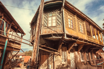 Fototapeta na wymiar Wooden grunge house with old facade, windows, decor in traditional style built in historical area of Tbilisi, Georgia country