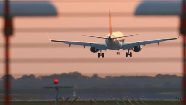 Commercial jet airplane landing on runway, filmed on super tele zoom lens