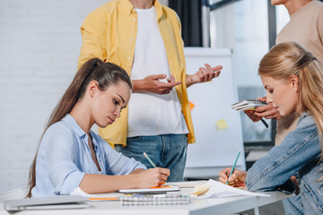 cropped image of businesswomen writing something during meeting in office