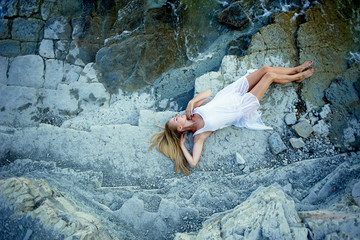 Beautiful blonde lying on the rocks, on the beach. Basking in the sun. Atmosphere of relaxation