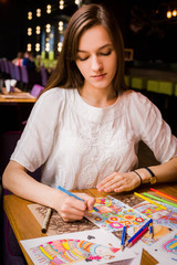 The girl is drawing in a cafe