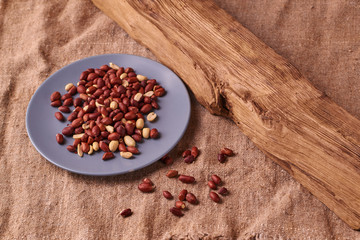Peanut snacks nuts eating snacks red peanuts peanuts fried peanuts on blue plate on sackcloth. selective focus