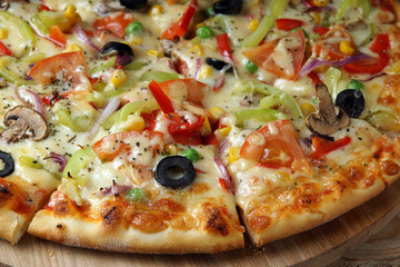 Bright pizza, cut into pieces, with vegetables and mushrooms