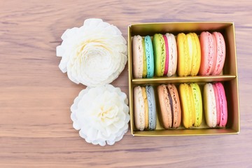 Top View of White Decorative Flowers and a Box Filled with Colourful French Macarons