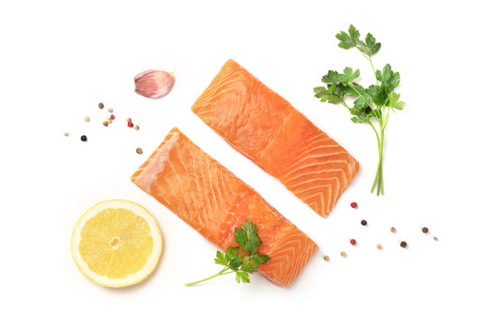 Slices of salmon with parsley, garlic, lemon, and pepper, on a white background with copy space, overhead photo