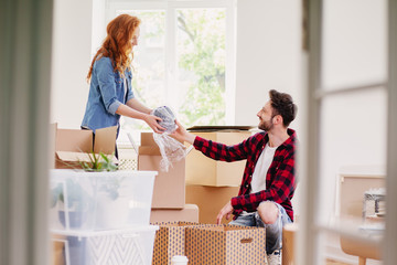 Couple unpacking stuff from carton boxes while furnishing interior