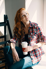 High angle on red haired woman with cup of coffee at home during renovation