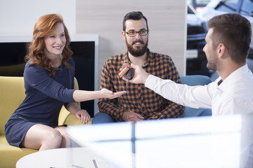 Smiling woman taking keys from car seller after buying transaction