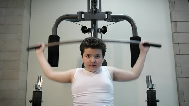 plump cute kid boy trains on the simulator fat burning, fat loss concept sports lifestyle