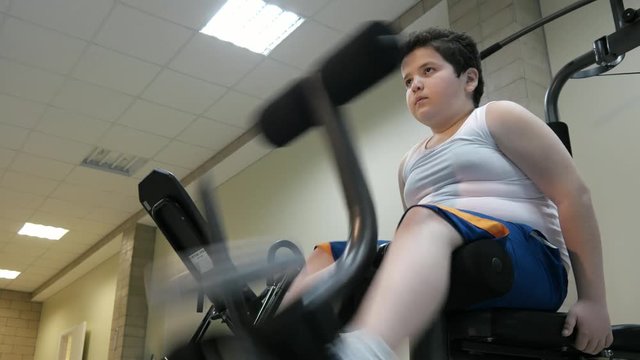 Child boy training on Sports Training Equipment at gym.big belly fat burning, concept counteracting obesity