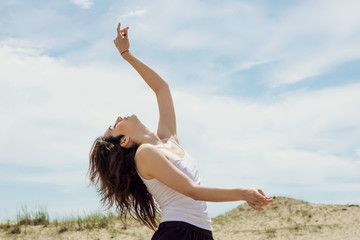 Young woman dances and extends her hands to the sky