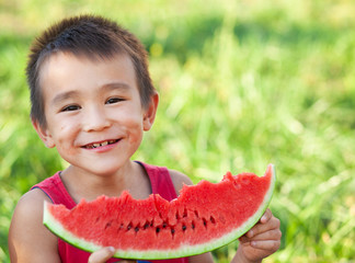 Happy smiling asian child eating watermelon in the garden. Kids eat fruit outdoors. Healthy snack for children. Little boy playing in the garden biting a slice of watermelon. - Powered by Adobe