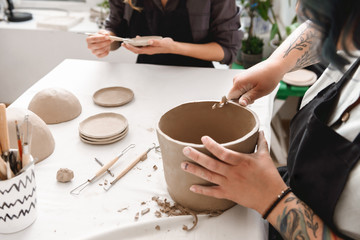 Fototapeta na wymiar Young woman making earthen pot in pottery workshop