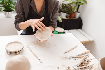 Fototapeta na wymiar Young woman making earthen pot in pottery workshop