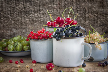 Various fresh summer berries in metal bawl on wooden background.