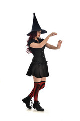 full length portrait of red haired girl wearing black witch costume and pointy hat.  standing pose,...