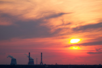 Fototapeta na wymiar Sunset over the city. CHP pipes, power station. Industrial landscape. Bright sunset over the horizon