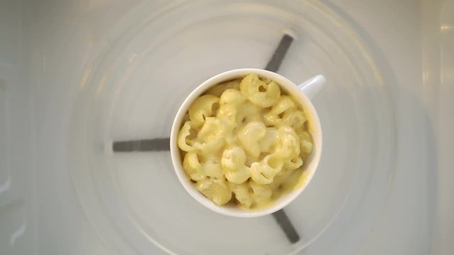 Making microwave mug meal. Macaroni and cheese in a mug microwaving top view