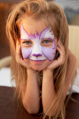 Pretty exciting blue-eyed girl of 5 years with a pink face painting