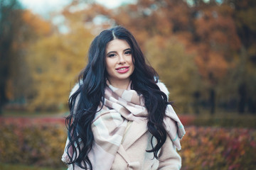 Fototapeta na wymiar Happy woman brunette in autumn park outdoors. Smiling girl