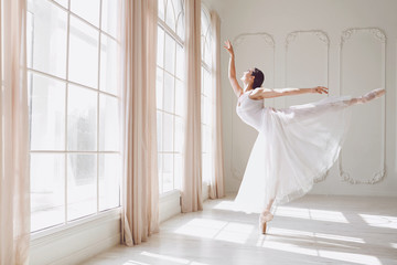 Obraz premium Ballerina dancing in a studio on white background window.