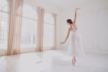 Ballerina dancing in a studio on white background window. © Studio Romantic