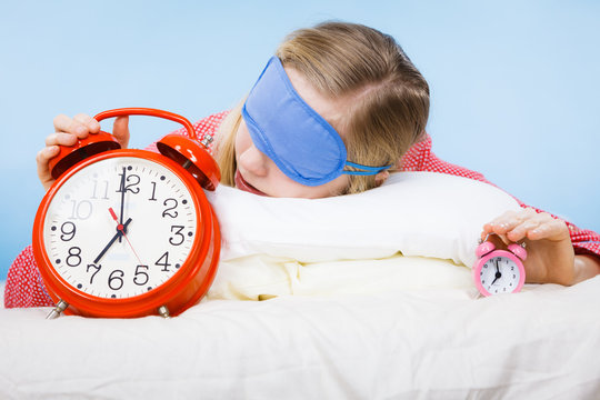 Sleeping woman wearing pajamas holding clock